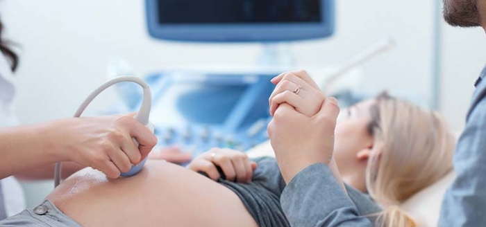 Werdender Vater unterstützt seine schwangere Partnerin beim Ultraschall Werdender Vater unterstützt seine schwangere Partnerin beim Ultraschall