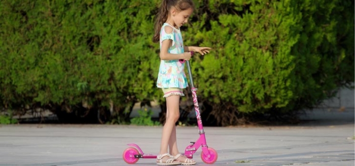 Mädchen fährt auf Roller-Scooter und übt sich in Bewegung Mädchen fährt auf Roller-Scooter und übt sich in Bewegung