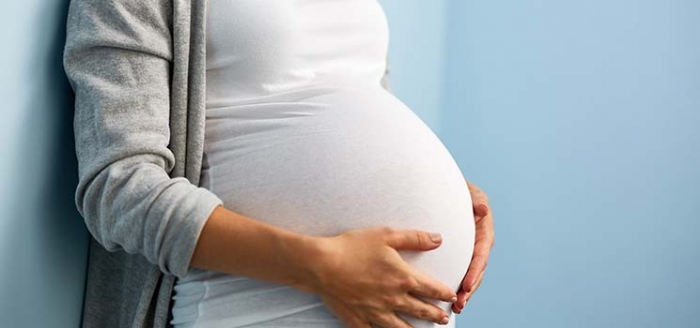 Schwangere schützt ihren Babybauch mit den Händen Schwangere schützt ihren Babybauch mit den Händen