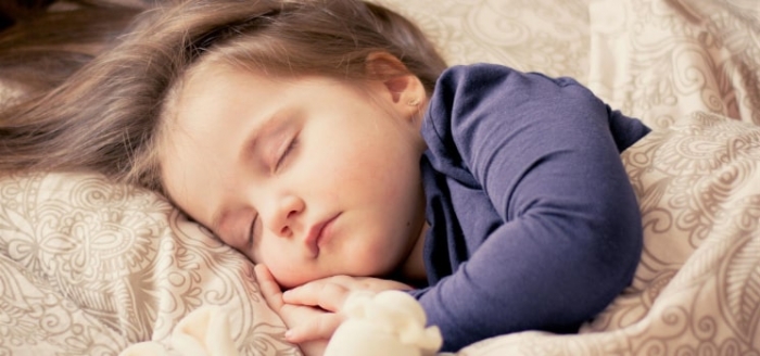 Mädchen schläft beruhigt mit Kuscheltier zur Schlafenszeit