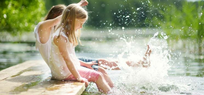 Mdchen pltschern mit den Beinen im See und genieen die Nhe zur Natur im Landleben