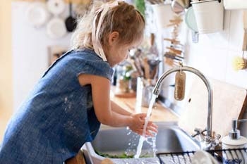 Mädchen wäscht sich vor dem Kochen die Hände Mädchen wäscht sich vor dem Kochen die Hände