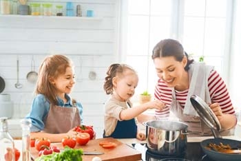 Mutter kocht mit Kindern am Kochtopf Mutter kocht mit Kindern am Kochtopf