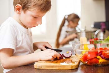 Kinder übernehmen Aufgaben in der Küche und schälen Gemüse Kinder übernehmen Aufgaben in der Küche und schälen Gemüse