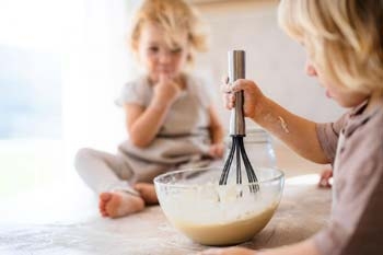 Kinder üben sich am Teig-rühren Kinder üben sich am Teig-rühren