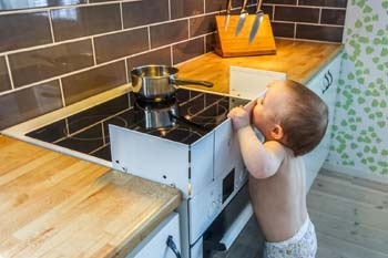 Kind greift an Backofen und Herd Kind greift an Backofen und Herd